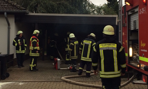 Unter dem Carport im Bergenrothweg zieht qualm hervor, die Einsatzkräfte sind auf der Suche nach der Brandursache. Foto: Werner Heise