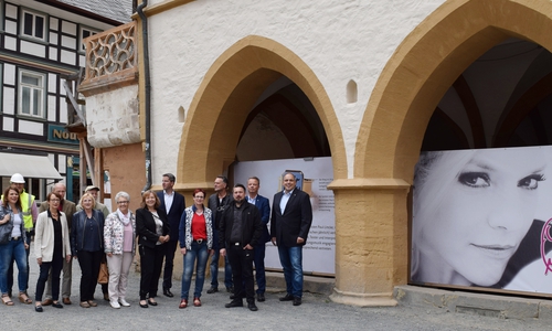 Dr. Oliver Junk, Organisatorin Susanne Roßdeutscher vom städtischen Fachdienst Kultur, Oliver Heinrich vom Goslarer Gebäudemanagement, Ideengeber Giovanni Graziano sowie
 die Sponsoren präsentieren die Planen mit Ina Müllers Gesicht unter den Rathausarkaden. Fotos: Stadt Goslar