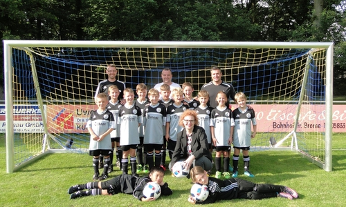 Die Trainer Patrick Stau, Meik Hecker und Toni La Rocca und die F-Jugend des FC Germania Parsau freuen sich über die neuen Fußballtore. Foto: Sparkasse Gifhorn-Wolfsburg