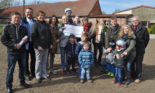  Unter Beobachtung von Therapiepferd Sam übergeben die Kiwanis-Mitglieder Bernhard Bolien (von links), Werner Kosanke, Almuth Ottmer, Angelika Ripken und Inge Nicolaus den Spenden-Scheck an die Vertreter der Lebenshilfe Karin Bartholomäus, Erik Roehring, Klaus Bätcke und die Kinder der Tigerenten-Gruppe. Foto: Lebenshilfe