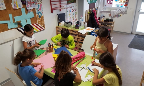 Die Kinder der Familien vom Schützenplatz basteln im Kinderraum der Wohnanlage schon voller Vorfreude bunte Dekoration für das Sommerfest. Foto: Stadt Wolfenbüttel