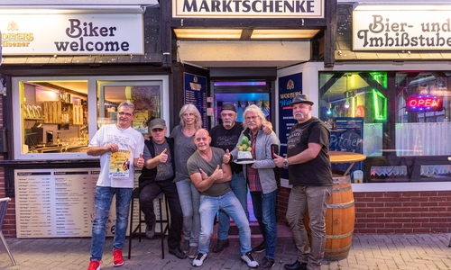Vor der Marktschenke: Betreiber Hansel, die Musiker Mark Beerell, Chaos Company, Musikschule Vielsaitig und Manfred Kramer mit seinem kleinen grünen Drachen Tabaluga. Foto: Andreas Behrens