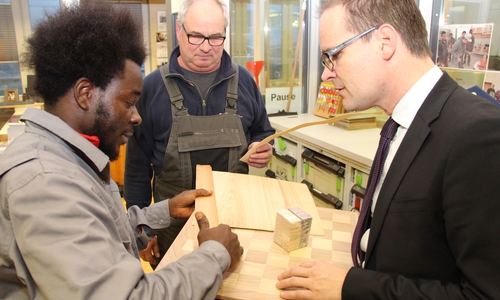 Cherif u Mamoudo aus Liberia (Westafrika) (links) überreicht Kultusminister Grant Hendrik Tonne (rechts) ein selbstgemachtes Schachbrett, das er im Rahmen des Integrationsprojekts "Berufsorientierung für Flüchtlinge (BOF)" angefertigt hat. Foto: Bauerfeld / Handwerkskammer