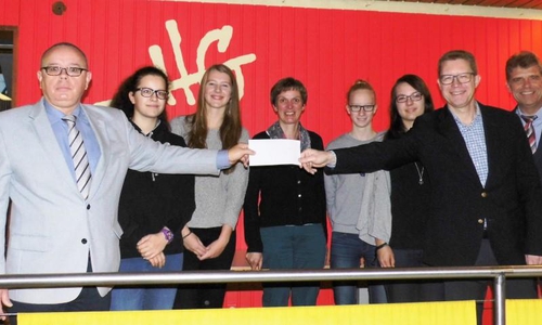 Symbolische Scheckübergabe im THG für die Patenschüler-AG: Andreas Meißler (l.,Ehemalige) und Dr. Ralf Luttmann (2. v. r.; Eltern- und Freundeskreis) im Beisein von Sozialpädagogin Manuela Glufke (4. v. l.) und Schulleiter Jürgen Siebert (r.) sowie den Patenschülerinnen Larissa Weidl, Marlen Bullinger, Wiebke Seifart und Malina Langemann. Foto: Andreas Meißler