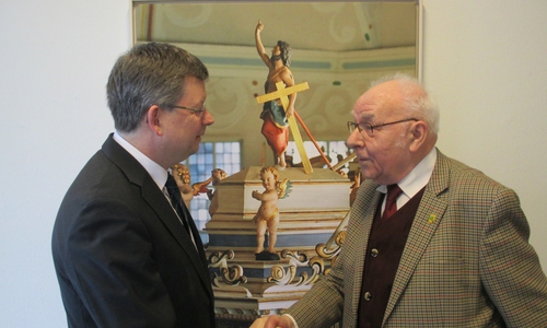 Landesbischof Christoph Meyns (.links) begrüßt Sicktes Altbürgermeister
Dieter Lorenz, im Landeskirchenamt. Vor dem Bild ,abgebildet der
Schalldeckel der Kanzel in der Wolfenbütteler St. Johannis Kirche. Foto: Lorenz 