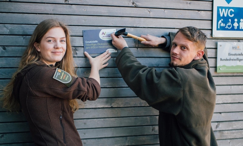 Sophie Schreiber und Jakob Husar bringen ein Schild an ihrer Einsatzstelle an. Foto: Nationalpark Harz