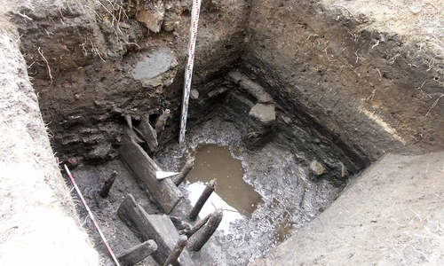 Im Bereich für eine spätere Rigole wurde in erstmals der alte nördliche Einfriedungsgraben der Katzhagenvorstadt erfasst. Der bis in 1,90 m Tiefe in den Niedermoortorf reichende Graben besaß am Nordrand eine hölzerne Uferbesfestigung. Nach Süden (hinten) ist er nicht in voller Breite ausgegraben. Foto: Thomas Budde