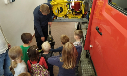 Tom Müller zeigt den kleinen Besuchern einen Rettungsspreizer. Quelle: Feuerwehr Flechtorf