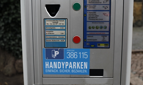 Aufkleber auf Parkautomaten weisen auf die Möglichkeit hin, auch per Handy Parkzeit zu buchen. Foto: Alec Pein