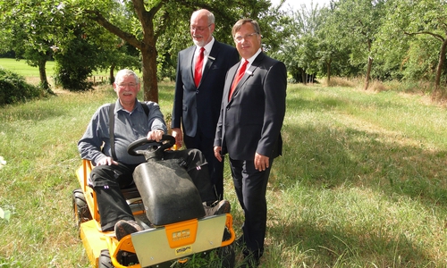 Große Arbeitserleichterung: Jürgen Kröger (r.) und Christian Eichler, Vorstände der Kultur- und Sozialstiftung der Sparkasse Gifhorn-Wolfsburg, lassen sich von Bernd Markert, Vorsitzender der NABU-Gruppe der Samtgemeinde Isenbüttel, den neuen Aufsitzrasenmäher für die Streuobstwiese zeigen. Foto: Sparkasse Gifhorn-Wolfsburg