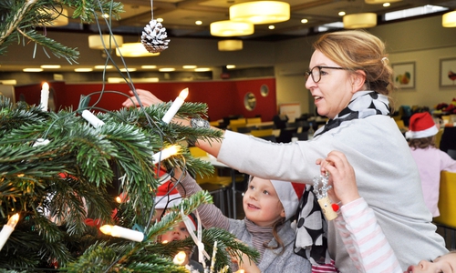 Dagmar Trentlage, die Leiterin der Kita Zwergenbutze des Studentenwerks OstNiedersachsen, mit Kindern beim Schmücken des Baumes. Foto: STUDENTENWERK OstNiedersachsen