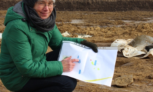 Die dunklen Verfärbungen in dem Lehmboden weisen auf die Pfähle der Häuser, die hier vor rund 2700 Jahren standen, berichtet Kreisarchäologin Dr. Monika Bernatzky.