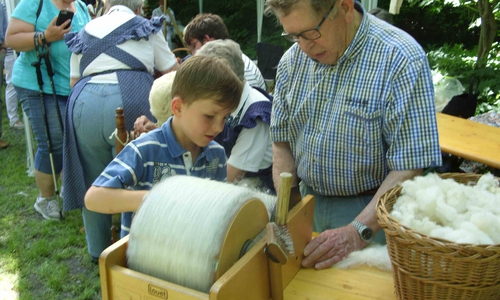 Mit der Kardiermaschine bürsten die Kinder die Wolle fein. Foto: Förderkreis Heimathaus Alte Mühle Schladen e.V. 