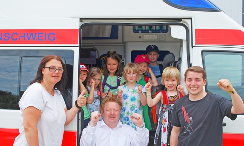 Jetzt heißt es Daumen für die Schule drücken. (v.l.n.r., erste Reihe) Erzieherin Jana Lehmann, Dienststellenleiter Marc Wegner und Auszubildender Max Grimm verabschiedeten sich von den Kindern der Johanniter-Kita "Die kleinen Murmeltiere". Foto: Steffen Ortlieb / Johanniter