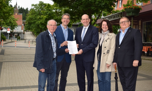 Matthias Wunderling-Weilbier (Mitte) überreicht den Aufnahmebescheid an Heinrich Wilgenbus (von links), Dr. Oliver Junk und Marion Siegmeier. Auch Axel Bender lässt sich diesen Meilenstein nicht entgehen. Im Hintergrund führt die Rathausstraße den Berg hinauf – einer der Schwerpunkte des Sanierungsprogramms. Foto: Stadt Goslar