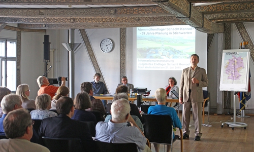 Moderator Michael Fuder (stehend) führte durch die Veranstaltung. Im Podium saßen (v. l.) der Physiker und Strahlenschutzexperte Wolfgang Neumann, Bürgermeister Thomas Pink und Ursula Schönberger von der Arbeitsgemeinschaft Schacht Konrad. Foto: Stadt Wolfenbüttel