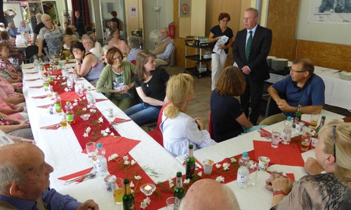 AWO-OV-Vorsitzender Hans-Joachim Kröger (stehend) bei der Begrüßungsrede im Kreise der Teilnehmenden beim traditionellen AWO-Spargelessen im „C 83“. Im Hintergrund Hannelore Schweigel (stehend mit Tischdecke) und links (stehend) AWO-Seniorenleiterin Marianne Geffers. Foto: Resch-Hoppstock