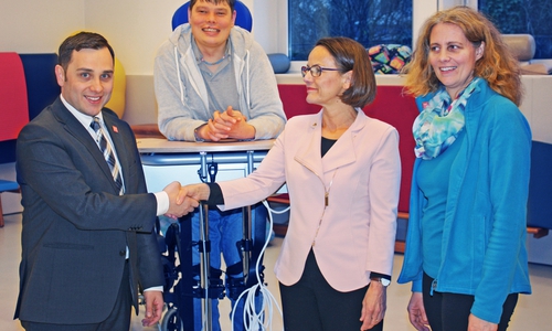 Ein Patient auf dem neuen elektrischen Stehtrainer, sowie davor Dr. Michael-Mark Theil, Chefarzt des IGN (1. von links), Dr. Isabelle Thormann, Präsidentin des Rotary-Clubs Braunschweig (2. von rechts) und Griseldis Zürner, Leiterin der Physiotherapie im IGN (1. von rechts). Foto: Evangelische Stiftung Neuerkerode 