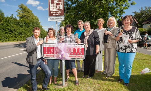 Feierliche Einweihung mit Sekt und Schleife: Sven Busse, Anja Voges, Elke Heß, Renate Lucksch, Wolfgang Müller, Petra Stolzenburg, Urte Schwerdtner, Vera Tietz und Brigitte Harder am neuen FrauenOrt-Schild an der Astfelder Straße. Foto: Alec Pein