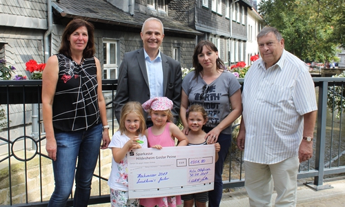 KiTa-Leiterin Sabine Schlüter (2. v. r.) übergibt zusammen mit Ortsbürgermeister Bernd Möller (r.) und Erzieherin Birgit Schlüter (l.) sowie mit Lilly, Charlotte und Lara (vorne: v. l. n. r.) den Spendencheck an Landrat Thomas Brych (2. v. l.) Foto: Landkreis Goslar
