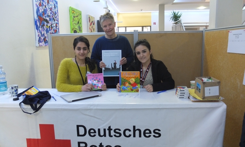 Foto (privat): Christiane Wagner-Judith bei der Übergabe der deutsch-arabischen Kinderbücher an Masi Khorshidi und Roshin Ali vom DRK
