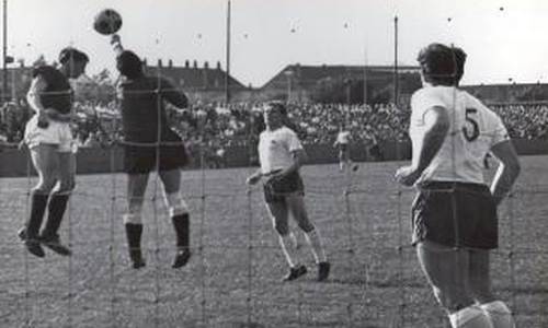 Lokalrivalen Derby1965: VfL-Torwart Winneke klärt vor FC-Mittelstürmer Zeisbrich: Szene aus dem Freundschafts-Lokalderby im Juni 1965. Die „Vertragsspieler“ des VfL aus der Regionalliga Nord besiegen die Landesliga-Amateure des 1. FC mit 4:3 – ein Fußball-Fest zum Abschluss der Saison 1964/65 vor 2.000 Zuschauern im Porschestadion Foto: Stadt Wolfsburg /Fotograf unbekannt.