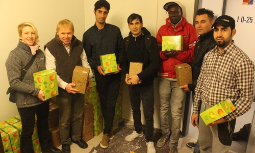 Beate Zgonc, Olaf Dalchow und einige Bewohner der Unterkunft bei der Übergabe der Apfelsaft-Boxen. Foto: Anke Donner 