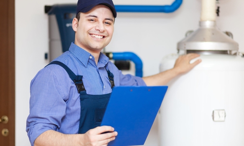 Ein lächelnder Servicetechniker vor einem Heizkessel. Foto: Bundesagentur für Arbeit