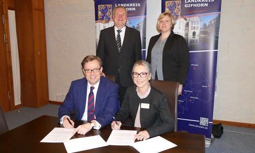 Landrat Dr. Andreas Ebel und Nela Bode, Geschäftsführerin des ASB Kreisverband Peine, unterzeichnen den Konzessionsvertrag über die Durchführung des Behindertenfahrdienstes im Landkreis Gifhorn. Hintere Reihe Kreisrat Rolf Amelsberg, Vorstand für Jugend, Gesundheit und Soziales, und Christiane Monitzkewitz (Arbeiter-‚ Samariter-Bund, ASB, Kreisverband Peine).