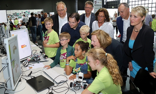 An der Station Bunte Roboterwerkstatt zeigen (ganz vorn, von rechts) Mai-Britt, Sara, Liam, Marc und Elias ihren Gästen Projektarbeiten und Erfindungen (dahinter von rechts) Laura Pooth (stv. GEW-Vorsitzende in Niedersachsen), Dr. Martin Hofmann (Leiter Volkswagen IT), Prof. Dr. Gesche Joost (Deutschlands Internet-Botschafterin), Elisabeth Pötsch (KIDScraft-Schirmherrin), "JJ" Johann Jungwirth (Chief Digital Officer, Volkswagen Konzern) sowie Ingo Stein und Gunter Wachholz (Betriebsräte bei Volkswagen). Foto: Volkswagen/Matthias Leitzke.
