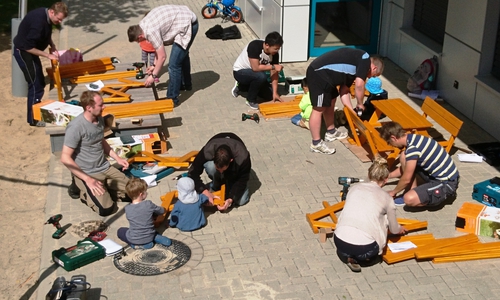 Eltern und Kinder der Kita "An den Teichen" schrauben gemeinschaftlich an den Sitzbänken. Foto: Stadt Wolfsburg
