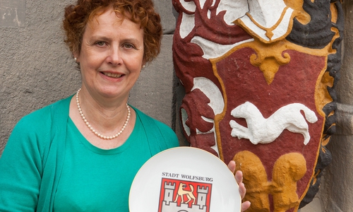 Dr. Karin Luys präsentiert das Wolfsburger Stadtwappen vor dem Schloss Wolfsburg. Foto: Stadtmuseum Wolfsburg
