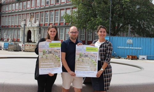 Vivien Strümpfler, Sebastian Kirchner und Anna Wohlert-Boortz präsentieren das Plakat zur Schlossplatzeinweihung vor dem neuen Brunnen. Foto: Marvin König