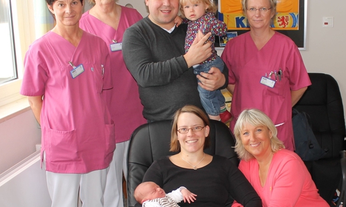 Von links: Stationsleitung Michaela Göbel, Hebamme Erika Bartz, Vater Kolja Mühe mit Tochter Louisa, Krankenschwester Denise Gabriel, Mutter und Kind mit entbindender Hebamme Angelika Cairns. Foto: Städtisches Klinikum