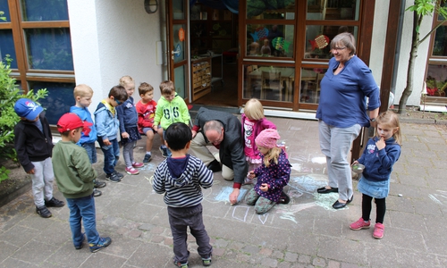 Pastor Friedhelm Siegemund demonstriert den Kindern seine Malkünste. Foto: Christoph Böttcher