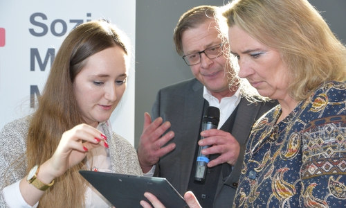 Bayerns Staatsministerin Kerstin Schreyer (rechts) trägt sich unter den Augen von Inna Ekkert und Andreas Ring in die "Kümmerer"-Liste ein. Foto: DRK