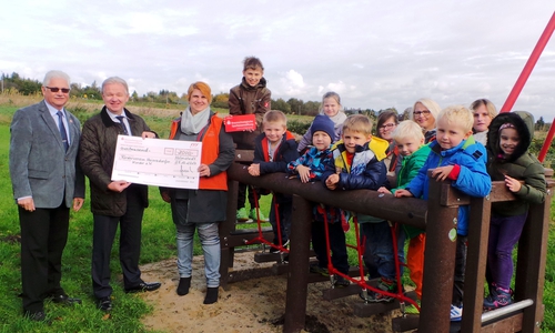 Bürgermeister Henry Bäsecke (li.) und die Vorsitzende des Fördervereins Hoiersdorfer Kinder Daniele Dunker nehmen im Beisein vieler Kinder und Vereinsvertreter die Spende der Braunschweigischen Sparkassenstiftung von Mathias Grote in Empfang. Foto: Stadt Schöningen