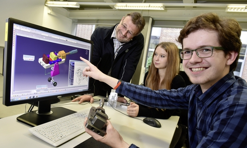 Adrien Hebert (17, vorn rechts) erkundet bei Volkswagen die Berufswelt, hier mit Ausbilder Sven Birke (links) und der Auszubildenden Lea Tiebe (18, Mitte) am Beispiel eines mobilen Schraub­stocks, wie Technische Produktdesigner Werkstücke am Bildschirm konstruieren. Foto: Volkswagen AG