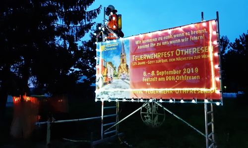 Die Feuerwehr kündigt das 52. Dorf- und Feuerwehrfest an allen Ortseingängen an. Schon jetzt zeigt sich Othfresens Kreativität, denn eine solche Ankündigung gab es noch nie: Ein Feuerwehrmann thront über dem mit blinkenden LEDs bestückten Plakat und löscht das im benachbarten Baum entzündete Feuer – mit echtem Wasser! Foto: Annabell Pommerehne