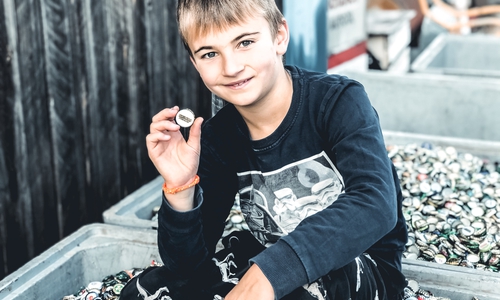Der 9-jährige Sohn des Vereinsgründers Felix Busse  präsentiert die Masse an gesammelten Kronkorken. Foto: Lila Hoffnung – CED und Darmkrebshilfe e. V.