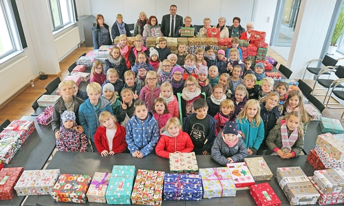 Lehrerinnen, Schülerinnen und Schüler der Grundschule Grasleben und die Weihnachtsdamen übergeben die liebevoll gepackten Schuhkartons an Samtgemeindebürgermeister Gero Janze. Foto: Samtgemeinde Grasleben