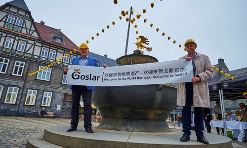 Mathias Derlin (Geschäftsführer GOSLAR marketing gmbh) und Gerhard Lenz (Geschäftsführer Weltkulturerbe Erzbergwerk Rammelsberg Goslar GmbH und Direktor der Stiftung Welterbe im Harz) heißen die Besucher auf Mandarin und Englisch auf dem Goslarer Marktplatz willkommen. Quelle: GOSLAR marketing gmbh/Fotograf Stefan Sobotta