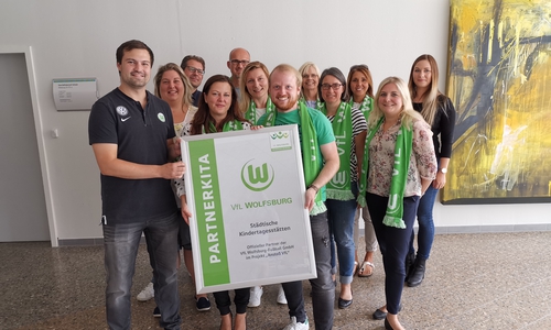 Robin Joop (vorne v.l. VfL Wolfsburg), Katharina Varga (Leiterin Geschäftsbereich Jugend) und Sören Henke (Fachbegietsleitung städtische Kitas) präsentieren die Partnerschaft im Projekt "Anstoß VfL". Foto: Stadt Wolfsburg