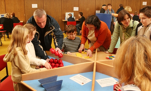 Kinder und ihre Eltern probieren sich am sogenannten Knobeltisch aus. Foto: Veranstalter