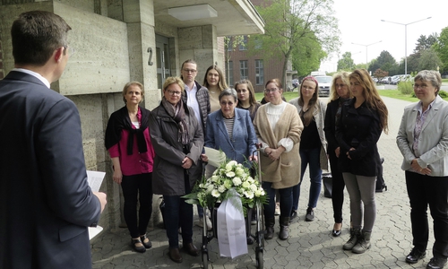 Sara Frenkel-Bass (Bildmitte, mit Blumengesteck) erinnert gemeinsam mit Auszubildenden und Mitarbeitern an die Opfer des Nationalsozialismus. Foto: Volkswagen AG