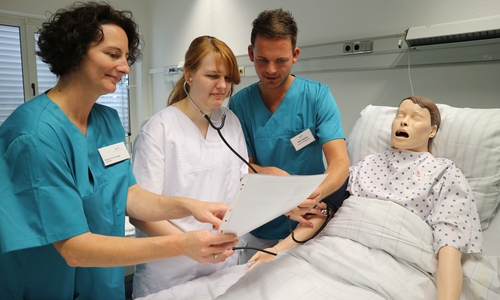 Die beiden Lehrer Chris Köhne und Katja Hunsrügge erklären der Auszubildenden Jaqueline Wilfling die Blutdruckmessung an der Pflegepuppe „Nursing Anne“.