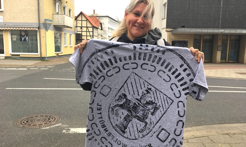Cathy präsentiert ihr Andenken: Ein bedrucktes T-Shirt mit dem Gully-Deckel-Motiv des Wolfenbütteler Wappens. Fotos: Nick Wenkel
