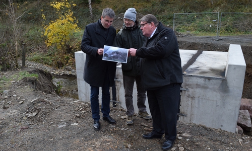 Wolfgang Lebzien (Mitte) zeigt Renke Droste (rechts) und Dr. Oliver Junk vor der neuen Brücke Fotos von den zerstörten Wegen in der Forst. Foto: Stadt Goslar