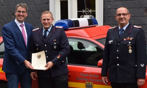 Oberbürgermeister Dr. Oliver Junk (li.) überreicht im Beisein von Stadtbrandmeister Christian Hellmeier (re.) die Ehrenurkunde an den neuen stellvertretenden Ortsbrandmeister der Ortsfeuerwehr Hahnenklee-Bockswiese: Sebastian Rau. Foto: Stadt Goslar
