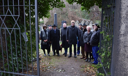 Die Projektbeteiligten freuen sich über das neue Metallgittertor, das auch in geschlossenem Zustand freien Blick auf den jüdischen Friedhof ermöglicht. Foto: Stadt Goslar